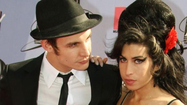 Amy Winehouse mit einem Mann mit Hut auf einem Event.