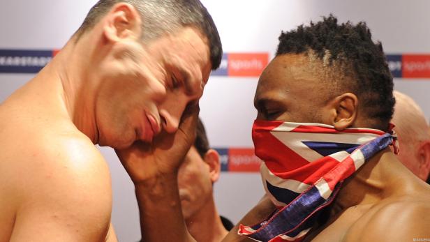 Zwei Boxer stehen Stirn an Stirn, einer mit einer Maske in den Farben der britischen Flagge.