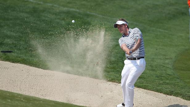 Ein Golfer schlägt einen Ball aus einem Sandbunker.