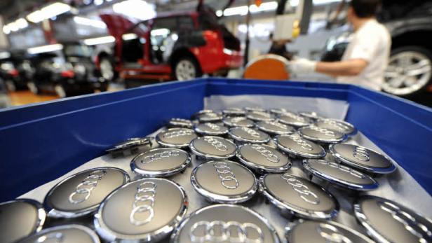Ein blauer Behälter gefüllt mit Audi-Emblemen in einer Fabrik.
