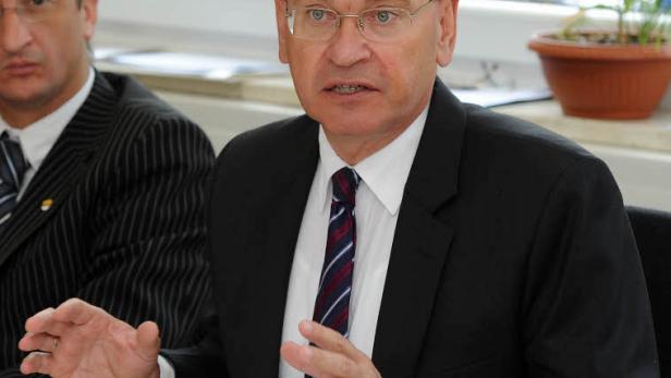 Ein Mann in einem Anzug gestikuliert während einer Pressekonferenz.