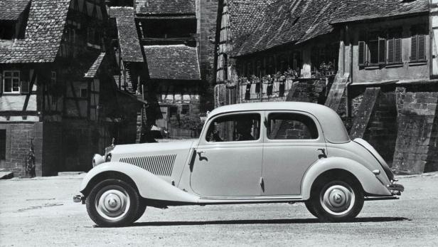 Ein Oldtimer von Mercedes-Benz vor Fachwerkhäusern.