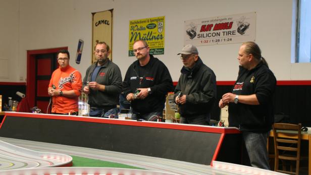 Fünf Männer stehen an einer Rennbahn für Slotcars und halten die Controller in der Hand.