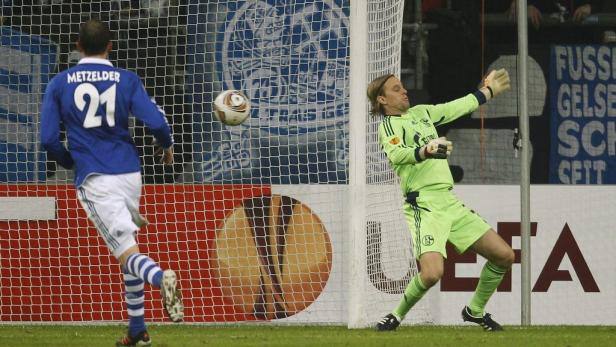 Ein Fußballspieler schießt auf das Tor, während der Torwart versucht, den Ball abzuwehren.