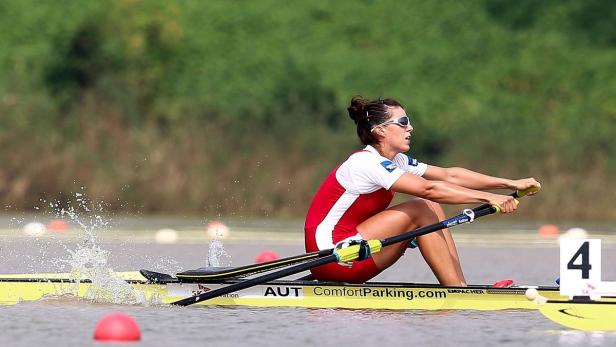 Eine Ruderin im rot-weißen Trikot rudert auf dem Wasser.