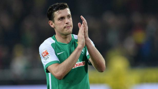 Ein Fußballspieler im grün-weißen Trikot klatscht in die Hände.