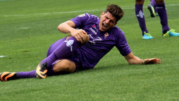 Ein Fußballspieler liegt schmerzerfüllt auf dem Rasen und hält sich das Knie.