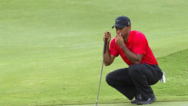 Tiger Woods kauert auf dem Grün und bereitet sich auf einen Putt vor.