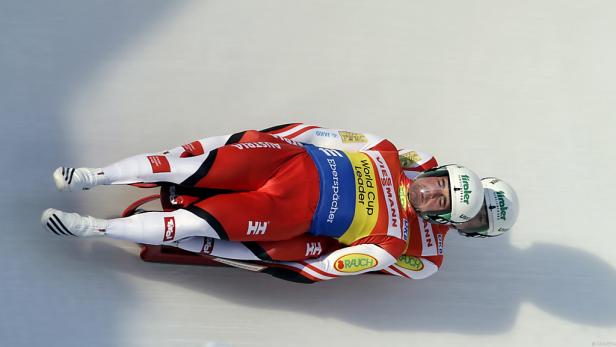 Ein österreichisches Doppelsitzer-Rodelteam rast eine Eisbahn hinunter.