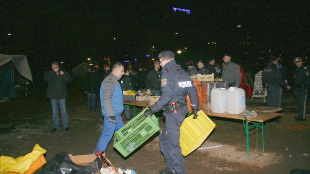 Polizisten räumen bei Nacht ein Lager auf.