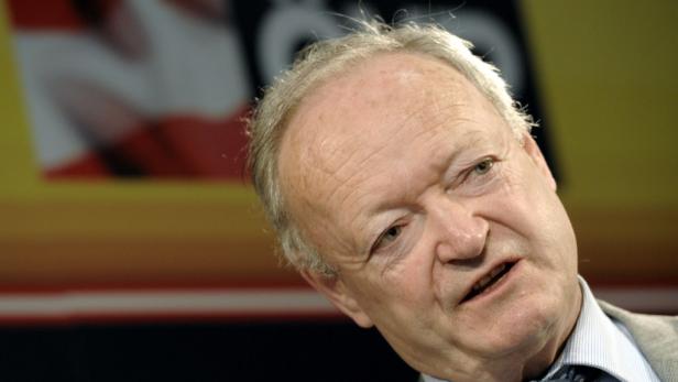 Ein älterer Mann mit grauem Haar schaut in die Kamera.