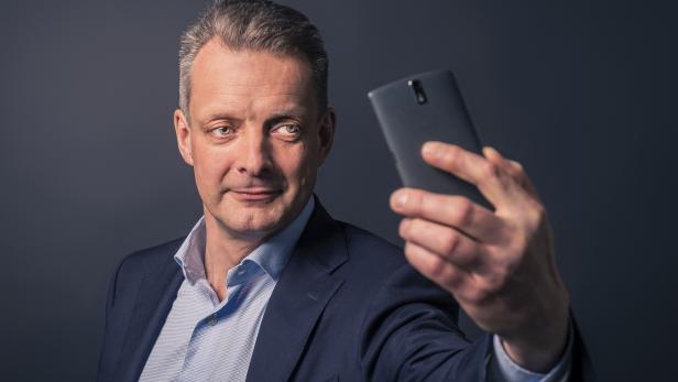 Ein Mann im Anzug macht ein Selfie mit seinem Smartphone.