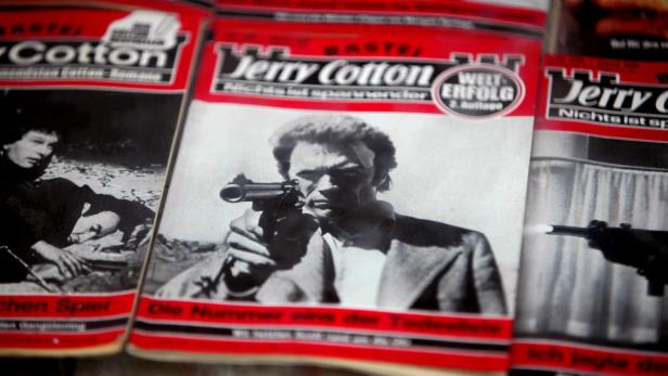 Cover von „Jerry Cotton“-Heften mit einem Mann, der eine Waffe hält.