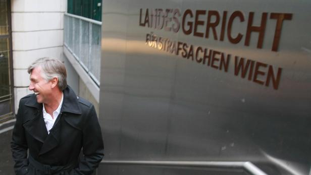 Ein lachender Mann vor dem Landesgericht für Strafsachen Wien.
