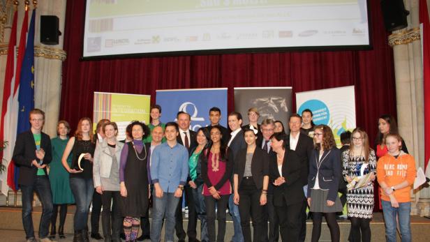 Eine Gruppe von Menschen steht auf einer Bühne vor einem Banner mit der Aufschrift „Sag’s Multi!“.