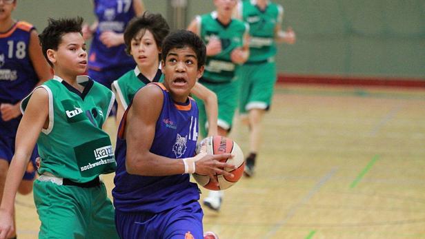Ein Jugendlicher dribbelt beim Basketballspiel den Ball.