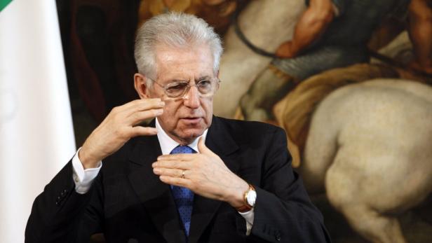 Mario Monti gestikuliert vor einem Gemälde.