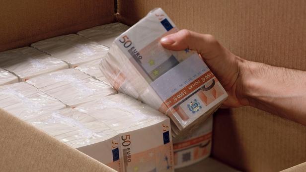 Eine Hand nimmt einen Stapel 50-Euro-Scheine aus einem Karton.