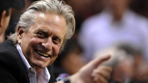 Michael Douglas lächelt und zeigt mit dem Finger auf etwas.