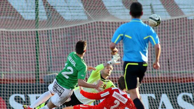 Ein Fußballspiel mit Spielern in Aktion vor einem Tornetz.