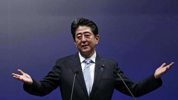 Shinzo Abe hält eine Rede vor einem blauen Hintergrund.