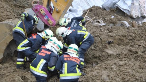 Feuerwehrleute arbeiten an einer Ausgrabungsstätte mit schwerem Gerät.