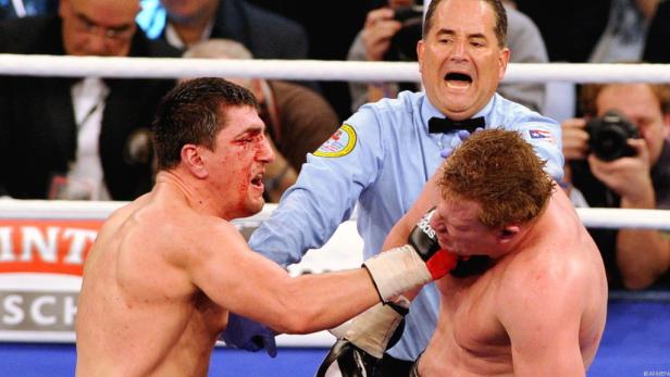 Ein blutiger Boxer wird während eines Kampfes von einem Schiedsrichter getrennt.