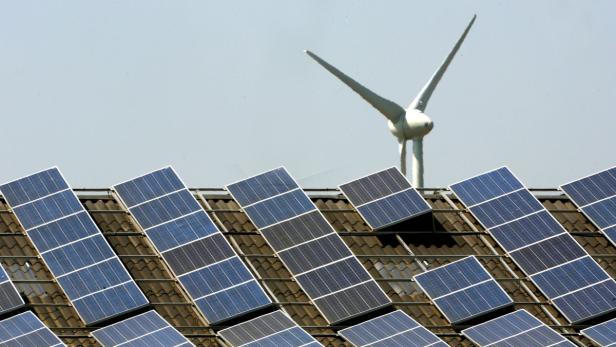 Auf einem Dach befinden sich Solarzellen und ein Windrad.