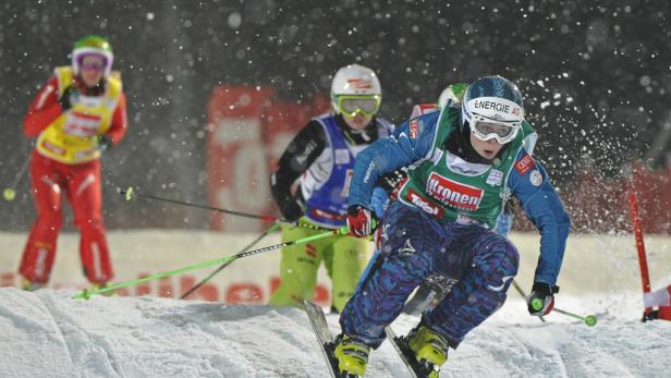 Ein Skirennläufer fährt bei Schneefall einen Hang hinunter.