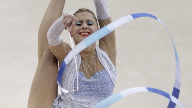Eine rhythmische Sportgymnastin führt eine Übung mit einem blau-weißen Band vor.