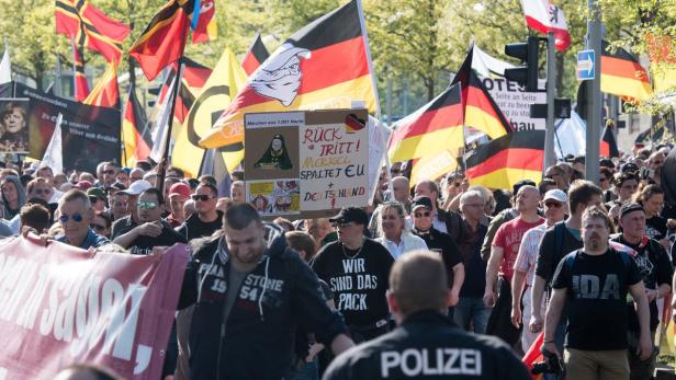 Eine Demonstration mit Deutschlandflaggen und Schildern gegen Angela Merkel.
