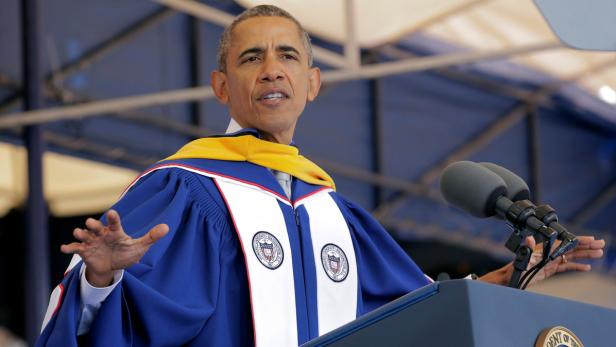 Barack Obama hält eine Rede in Talar und mit Mikrofonen vor sich.