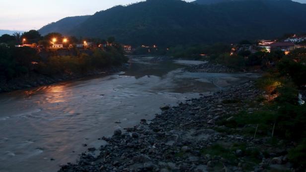 Ein Fluss fließt durch eine bergige Landschaft in der Abenddämmerung.