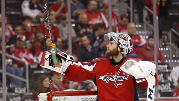 Ein Eishockeytorwart der Washington Capitals spritzt Wasser aus einer Gatorade-Flasche.
