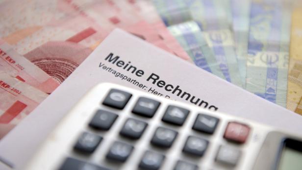 Eine Rechnung liegt auf einem Stapel Euroscheine, im Vordergrund ein Taschenrechner.