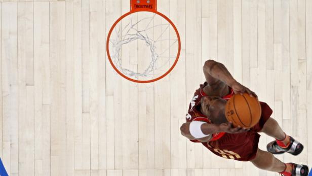 Ein Basketballspieler wirft einen Ball in den Korb.