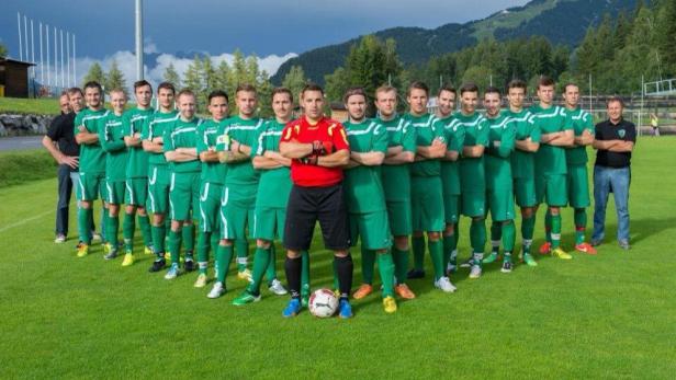 Eine Fußballmannschaft posiert mit einem Schiedsrichter für ein Gruppenfoto.