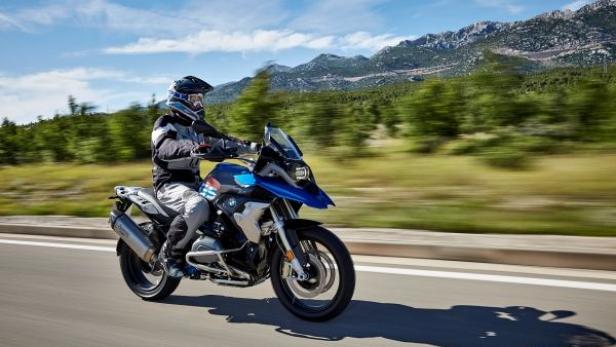 Ein Motorradfahrer fährt auf einer BMW-Maschine auf einer Landstraße.