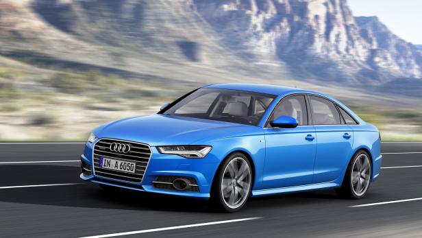 Ein blauer Audi A6 fährt auf einer Straße vor einer Bergkulisse.