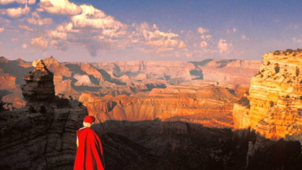 Eine Person in rotem Umhang blickt auf den Grand Canyon.