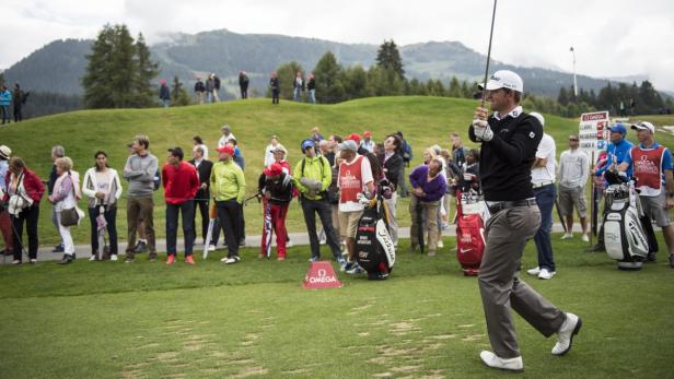 Ein Golfer schlägt vor einer Zuschauermenge auf einem Golfplatz ab.