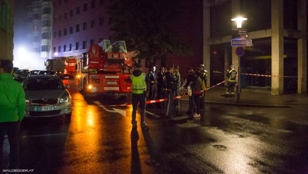 Ein Feuerwehreinsatz auf einer nassen Straße bei Nacht.