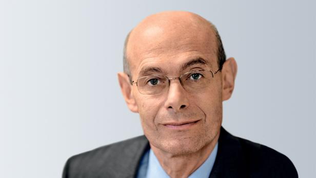 Ein Mann mit Brille, Anzug und Krawatte blickt in die Kamera.
