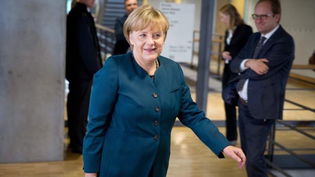 Angela Merkel in einem blauen Blazer lächelt in die Kamera.