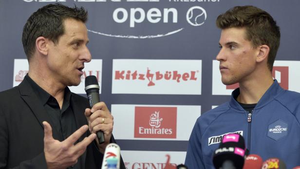 Zwei Männer stehen vor einem Banner des Kitzbühel Open Tennisturniers.