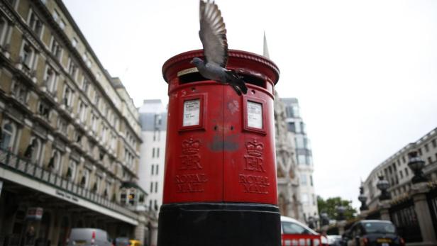 Eine Taube fliegt von einem roten Briefkasten der Royal Mail in London weg.