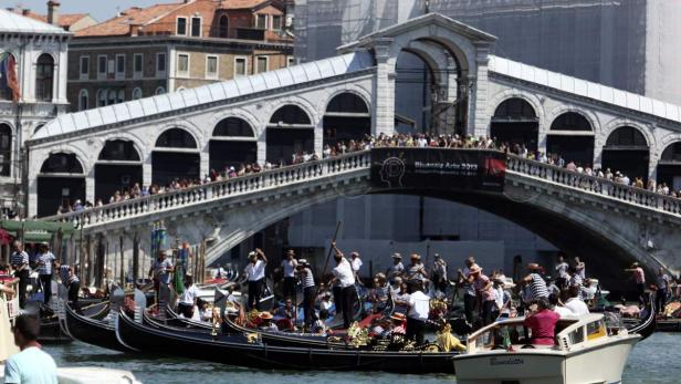 Gondeln fahren auf dem Canal Grande in Venedig unter der Rialtobrücke hindurch.