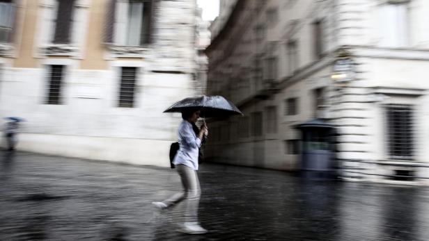 Ein Tourist schlendert im Regen durch Rom.