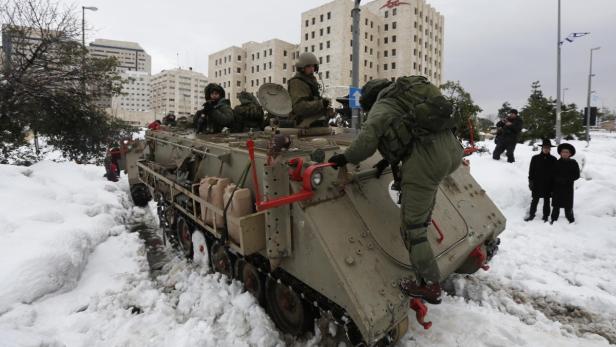 Soldaten auf einem Militärfahrzeug fahren durch eine verschneite Stadt.