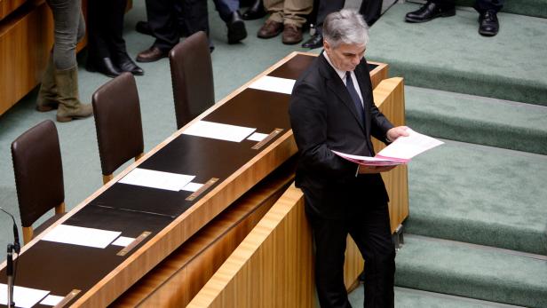 Ein Mann im Anzug liest ein Dokument in einem Sitzungssaal.